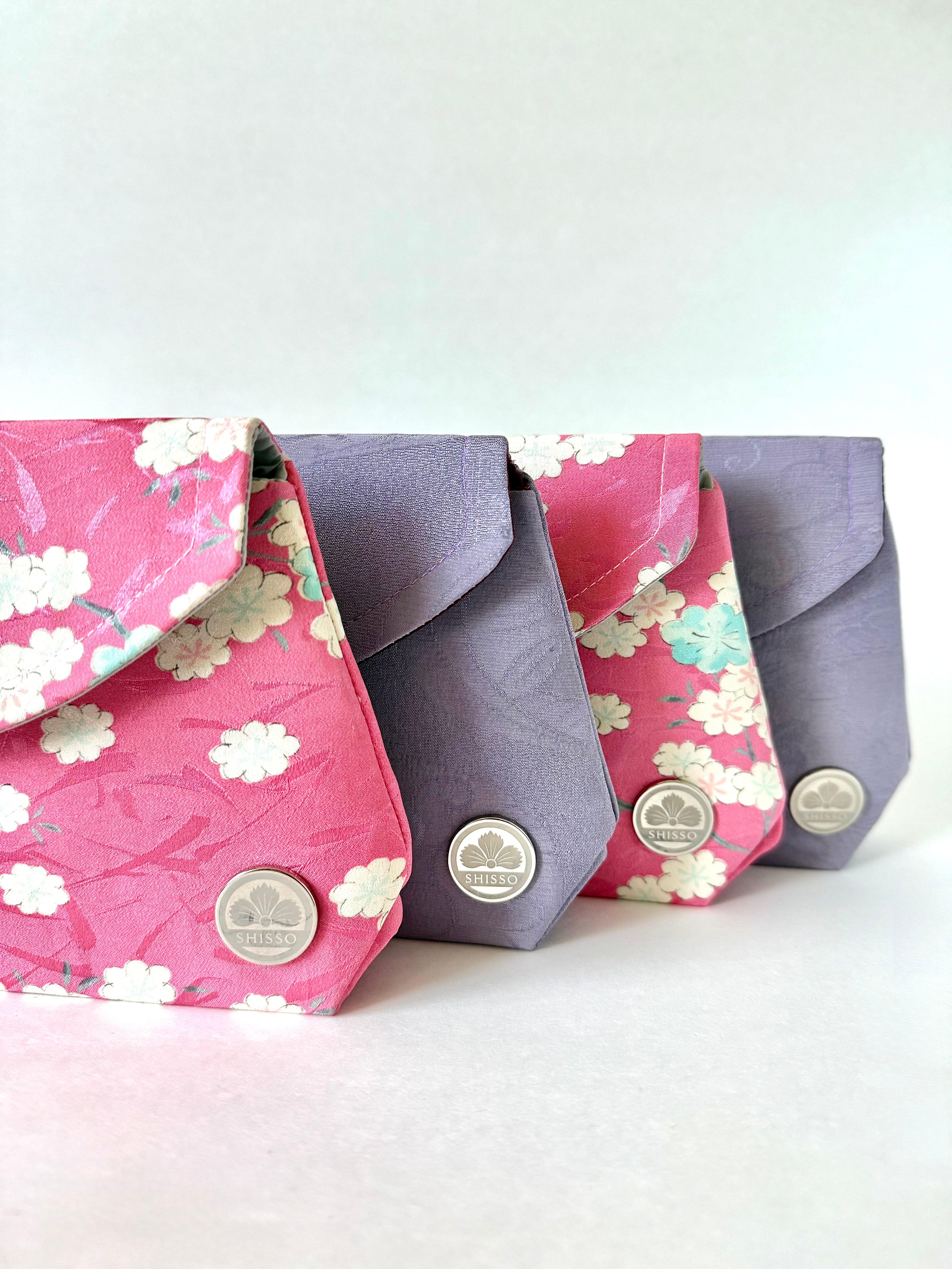 Two pink floral clutch bags and two purple clutch bags on a white background