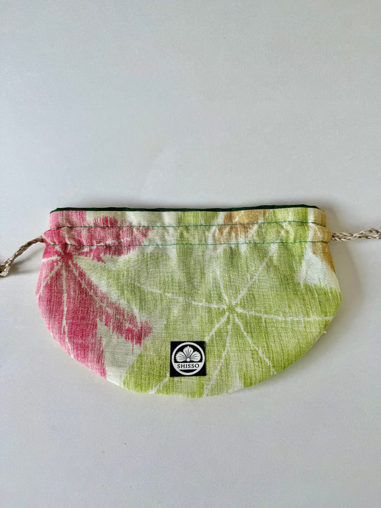 frontal view of flat laying beige kimono silk pouch with large green and red maple leaf motifs and yellow accents