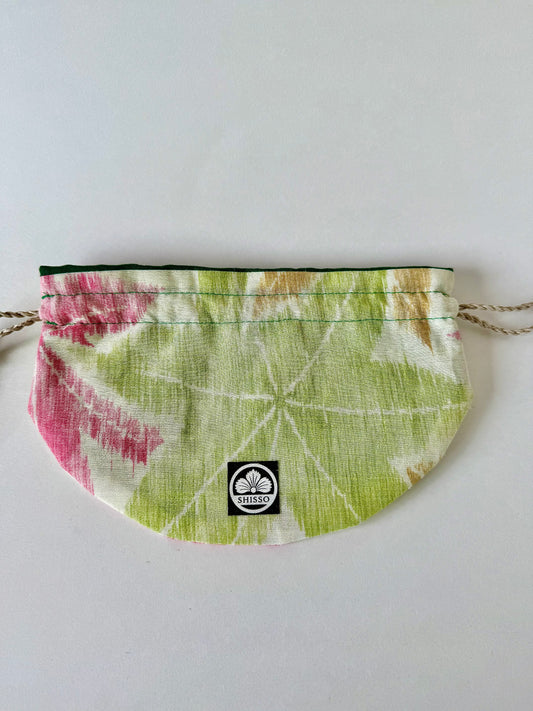 Flat lay of beige woven kimono silk with green, red, and yellow Japanese maple leaf designs in autumn hues