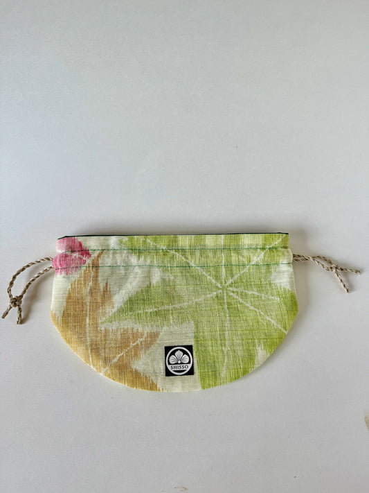 Flay laying off white textured kimono silk drawstring pouch with green, yellow, and red maple leaf designs in autumnal hues