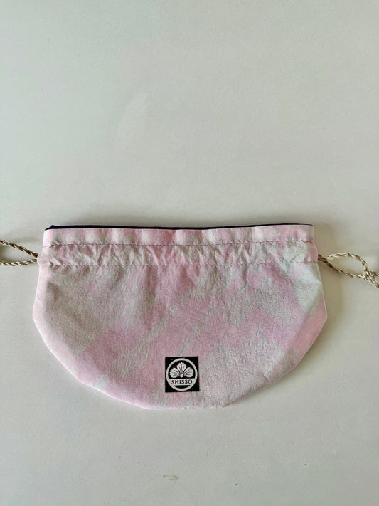 Pink kimono silk drawstring pouch with darker pink accents laying flat in a “D” shape