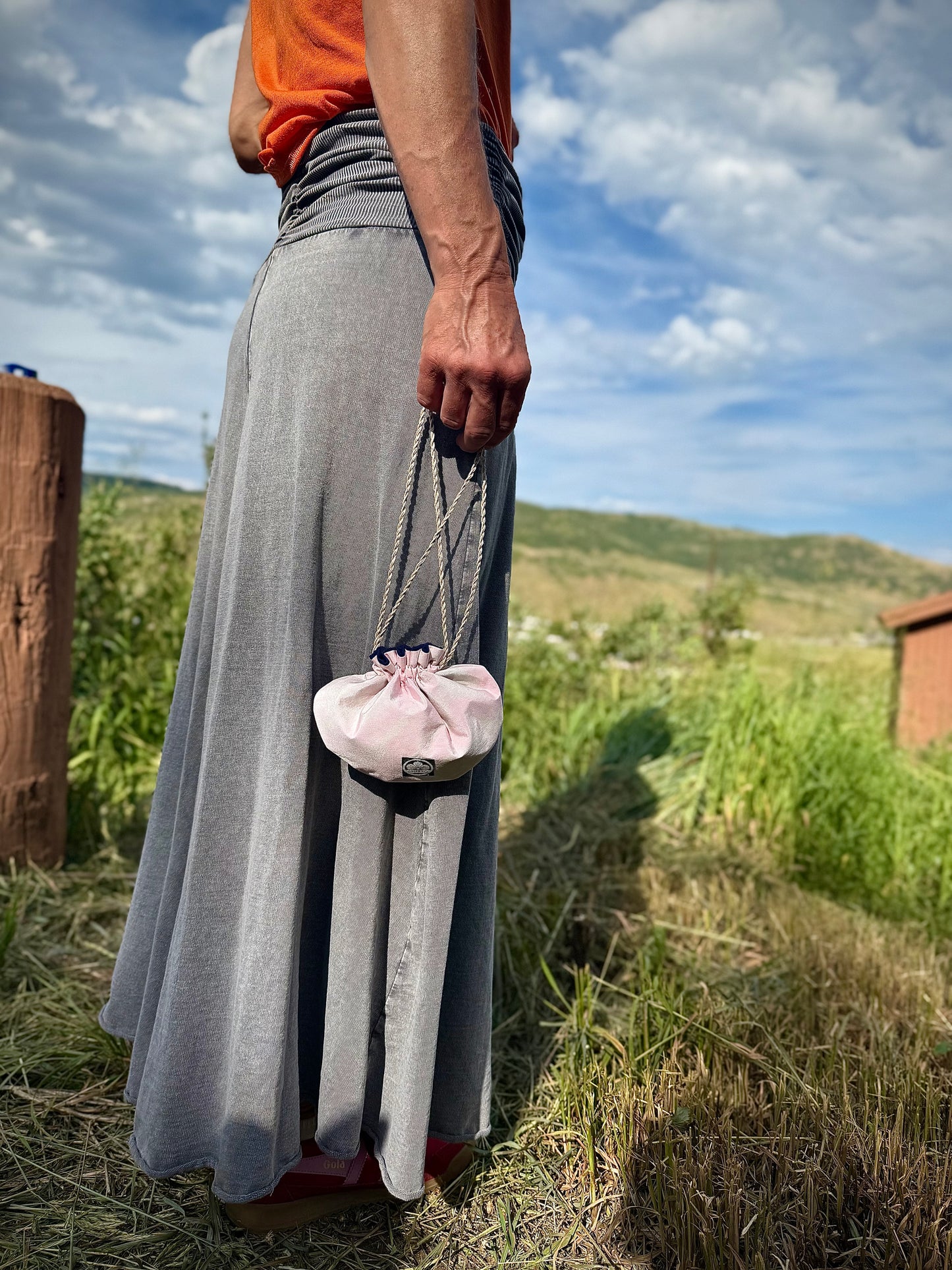 Light pink kimono silk with darker pink accents being carried in hand by hemp drawstrings in nature