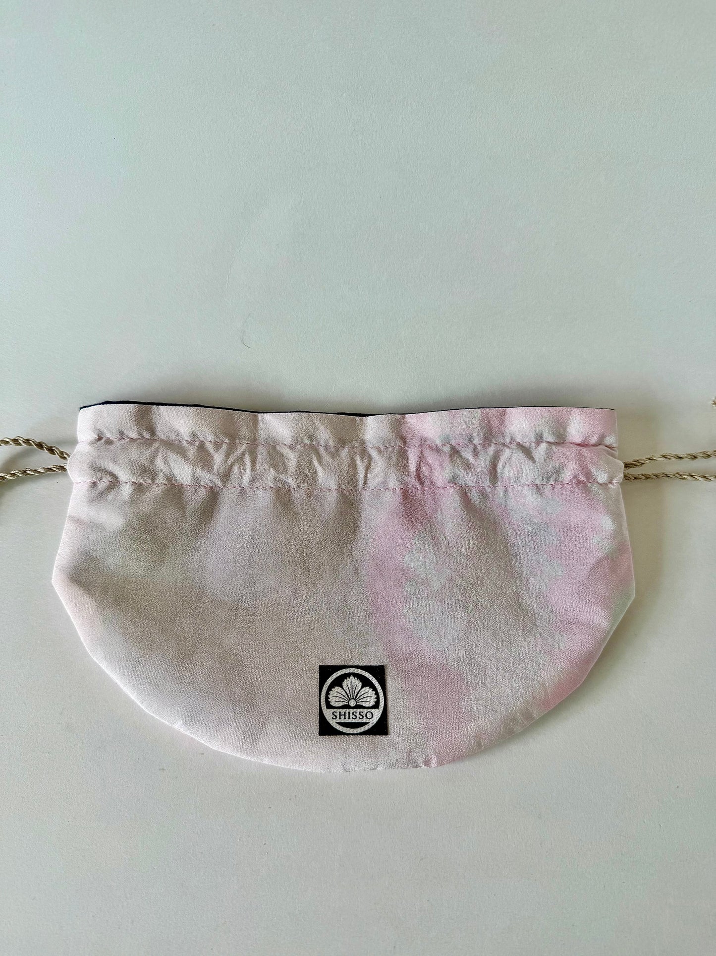 Front view of flat laying pink kimono silk drawstring bag with darker pink accents