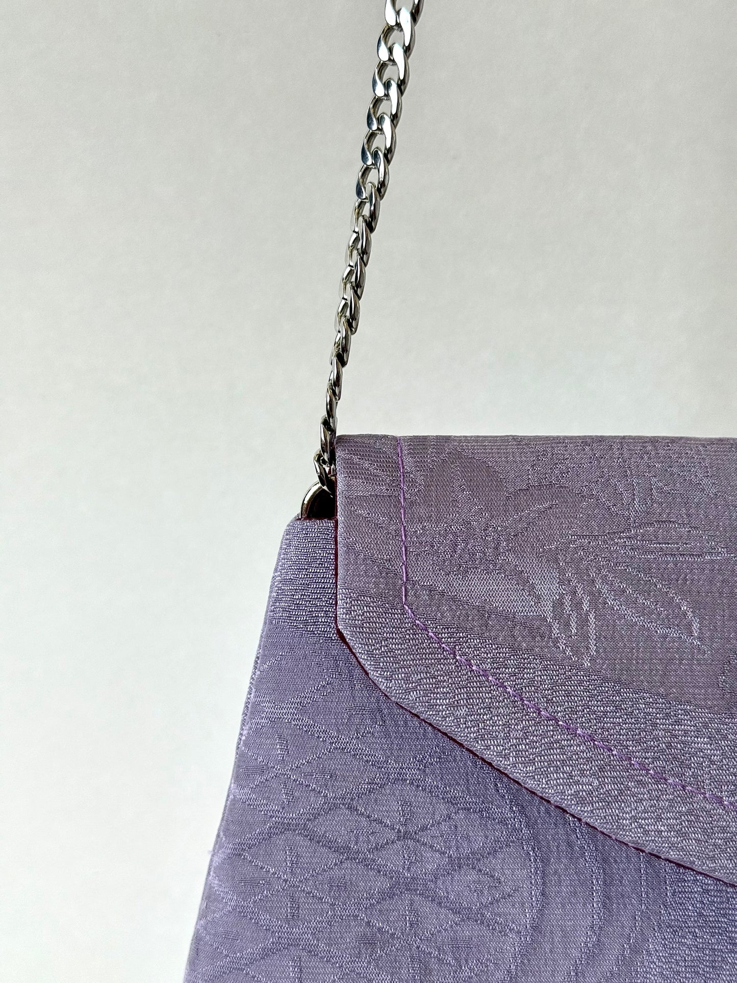 Metal chain strap discreetly attached to a purple kimono silk clutch