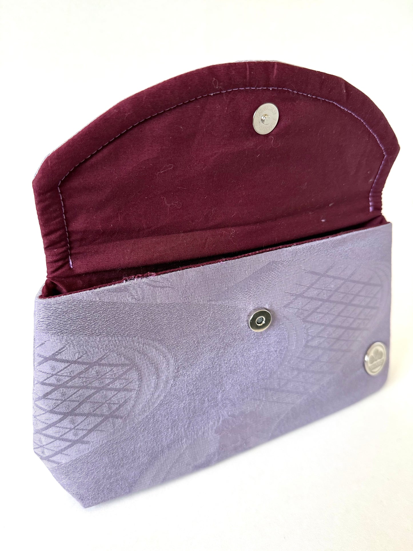 Close-up of hand stitched seam on purple vintage kimono Chirimen silk with geometric patterns and subtle sheen