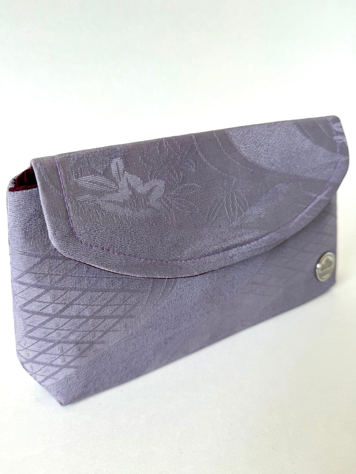 Front left view of purple chirimen silk clutch featuring floral and diamond patterns