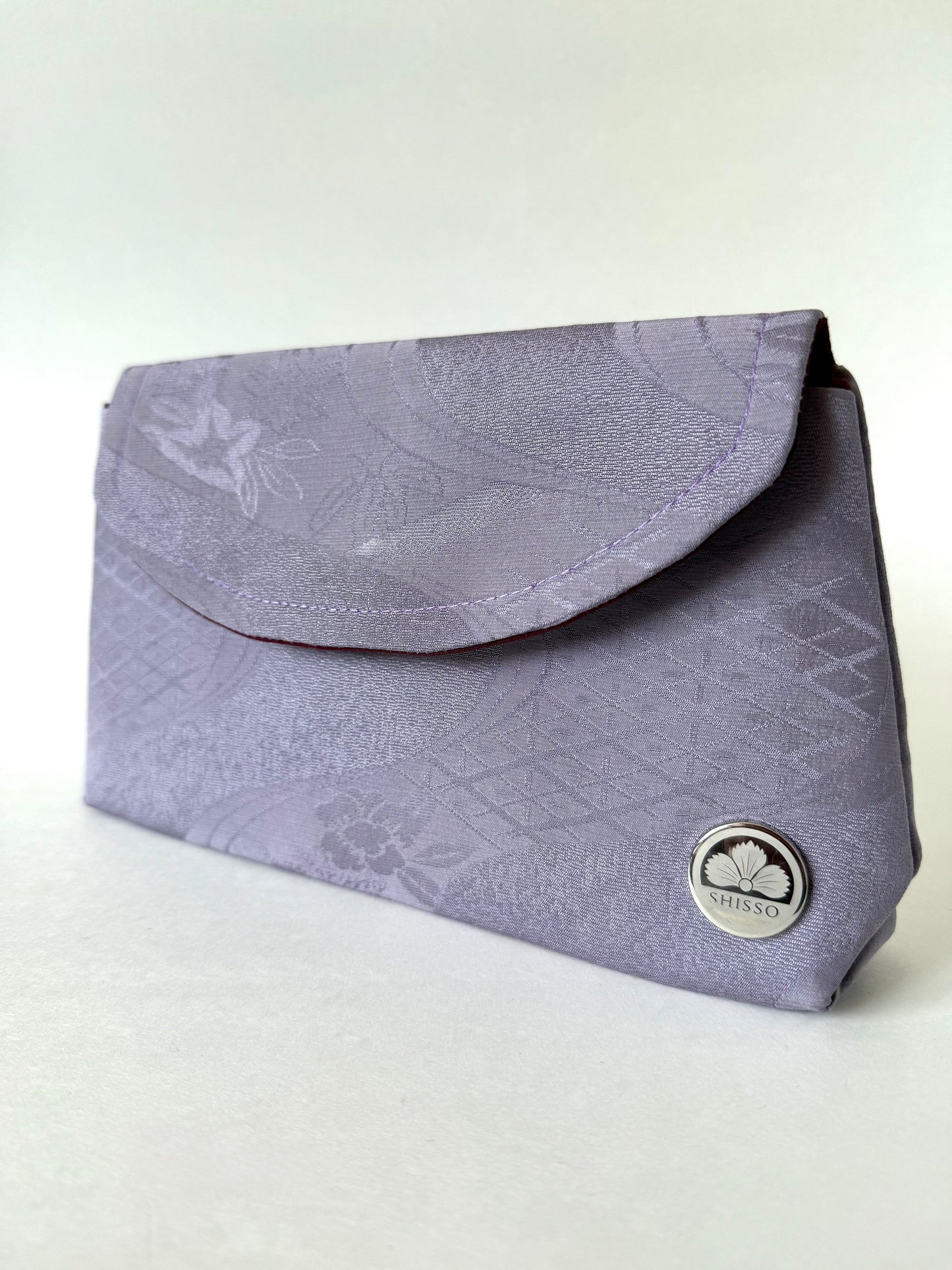 Front view of purple chirimen silk clutch with floral, geometric, and river motifs