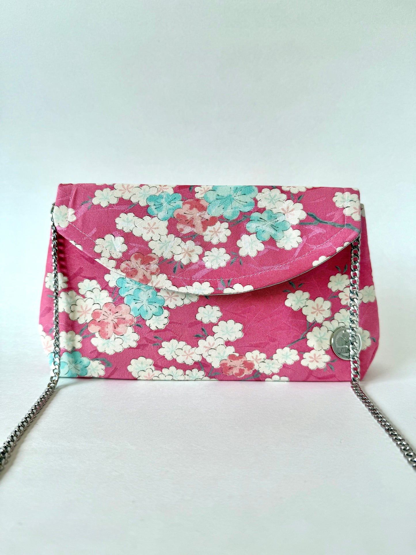 Pink, silk kimono fold over handmade clutch bag with silver colored metal chain featuring white, blue and pink sakura blossoms