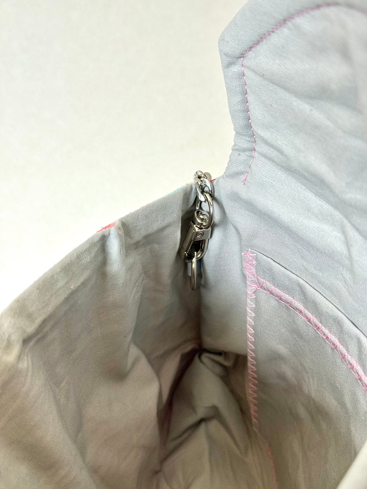 Close up of detachable chain connected to silver cotton interior of kimono silk clutch bag