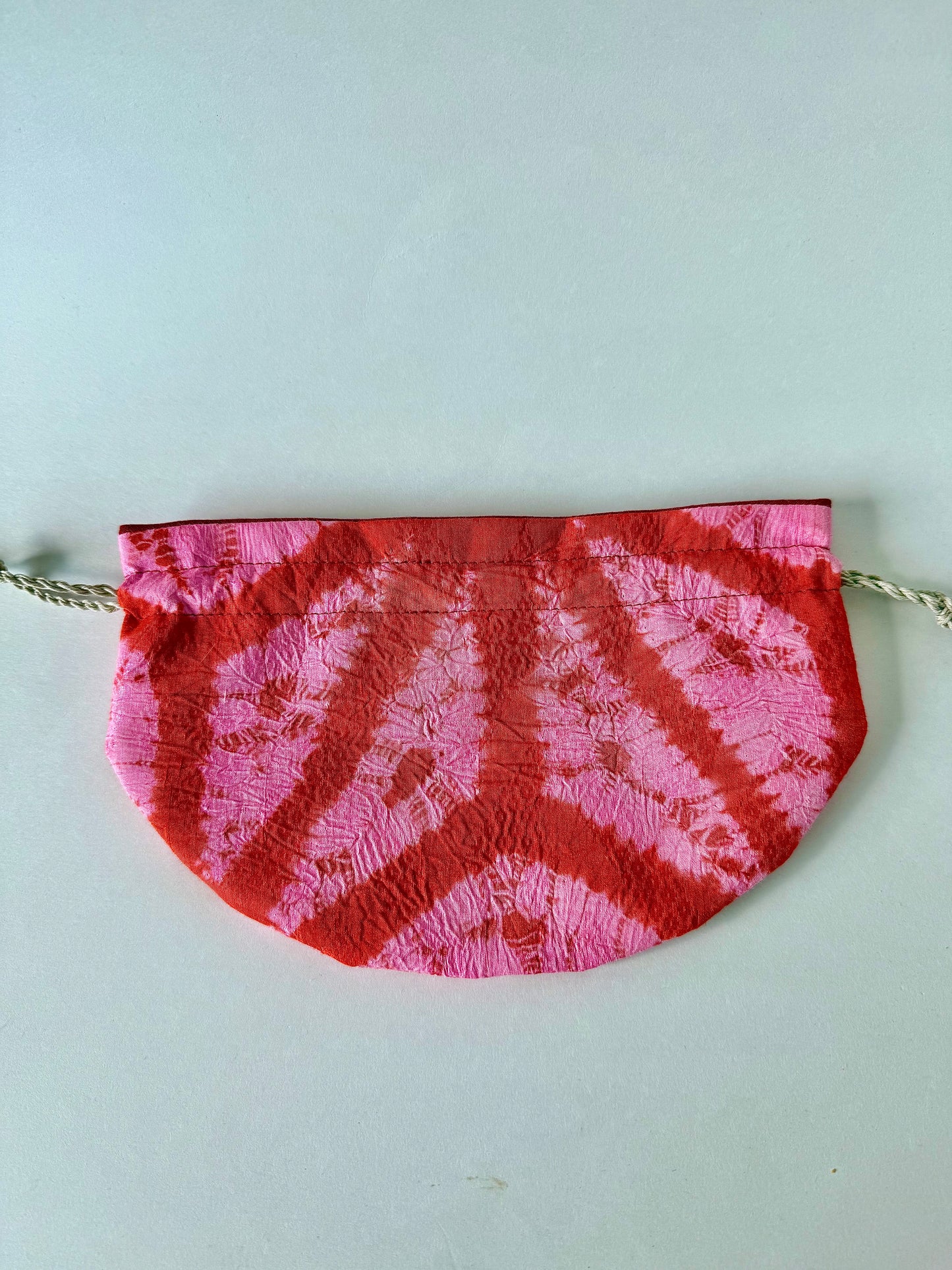Back view of red and pink Upcycled kimono silk drawstring pouch with crepe and ripple texture laying flat