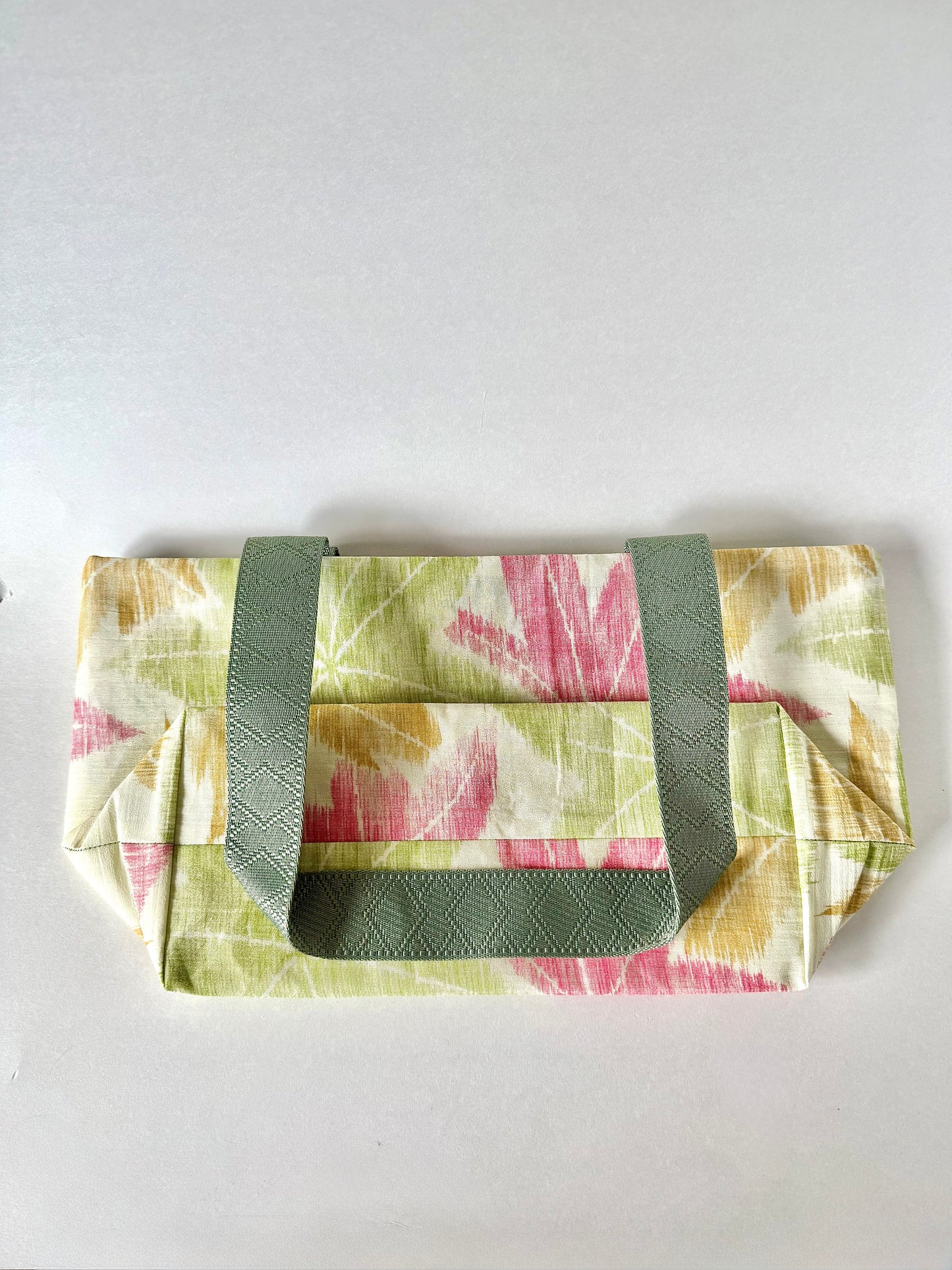 Backside of textured kimono silk tote bag folded flat with dark sage green handle folded on top