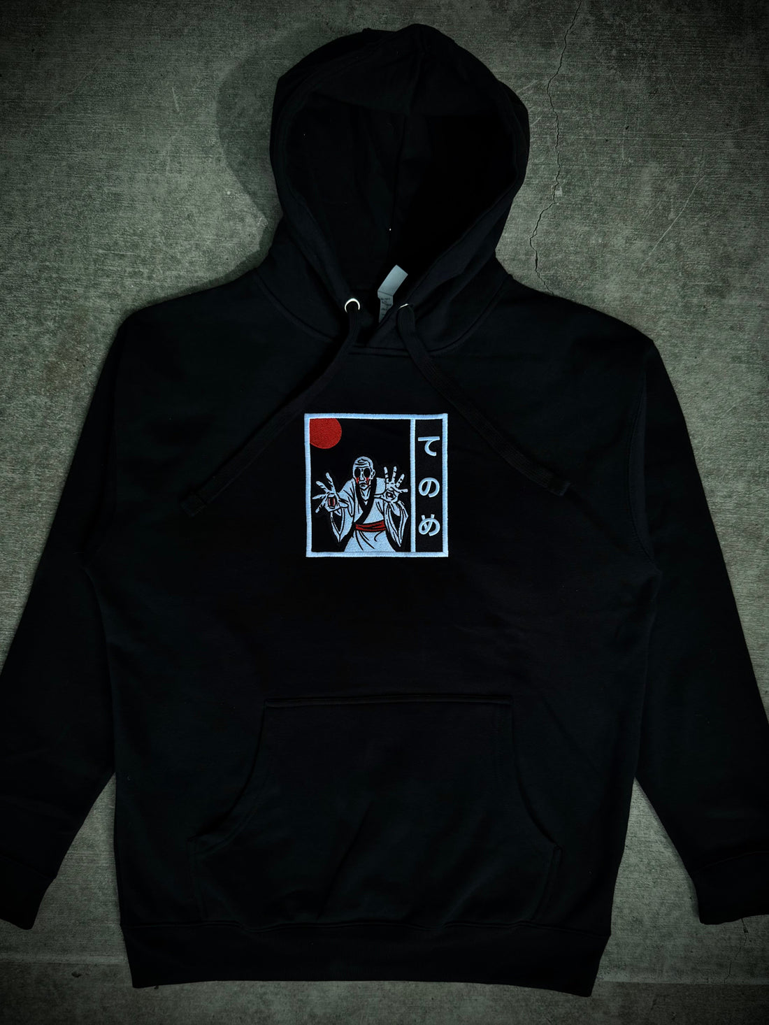 Black hoodie with embroidered yokai design in black and white with red accents.