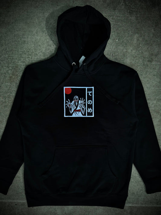 Black hoodie with embroidered yokai design in black and white with red accents.