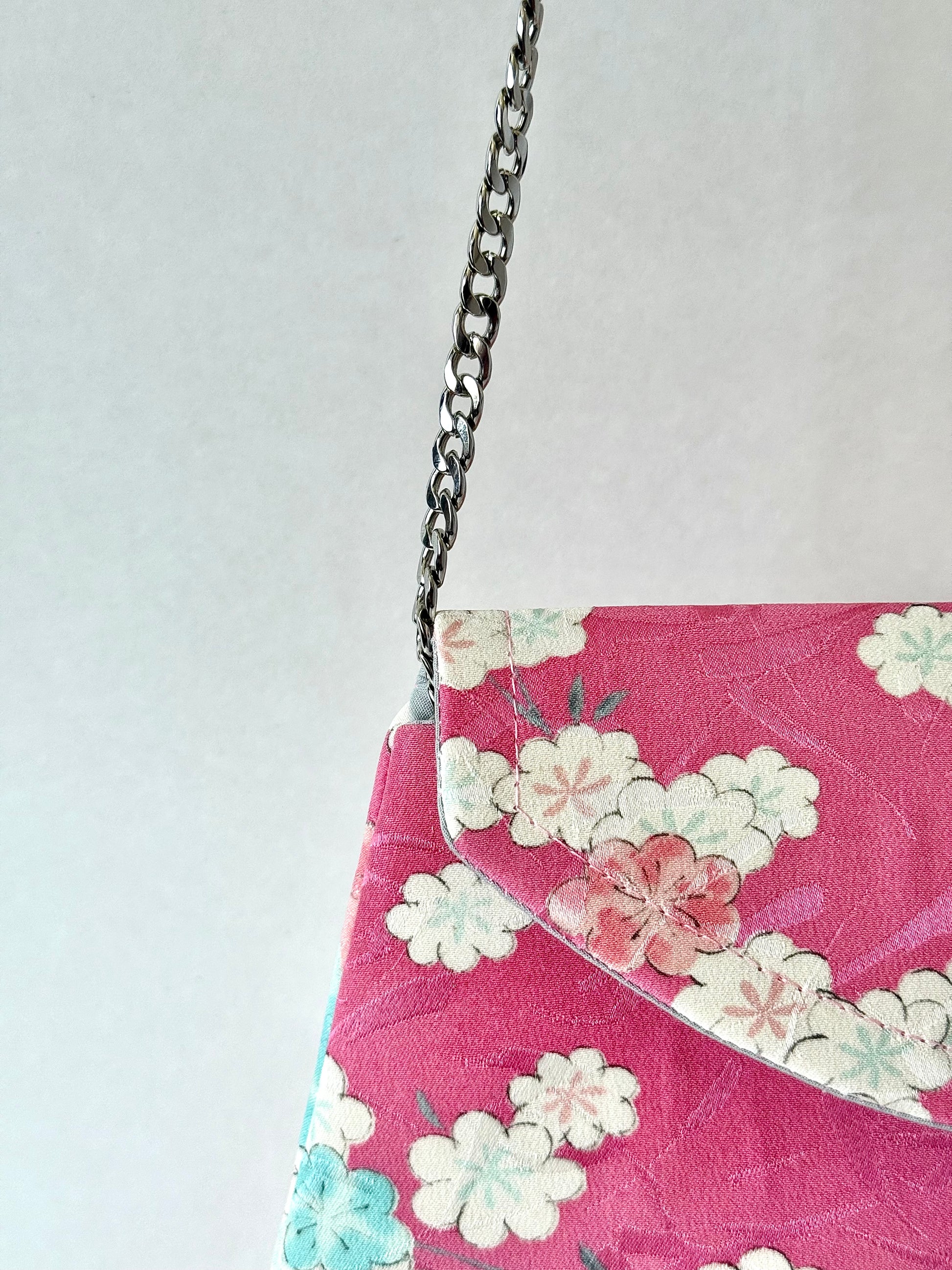 Detachable metal chain strap connected to pink kimono silk fold over clutch