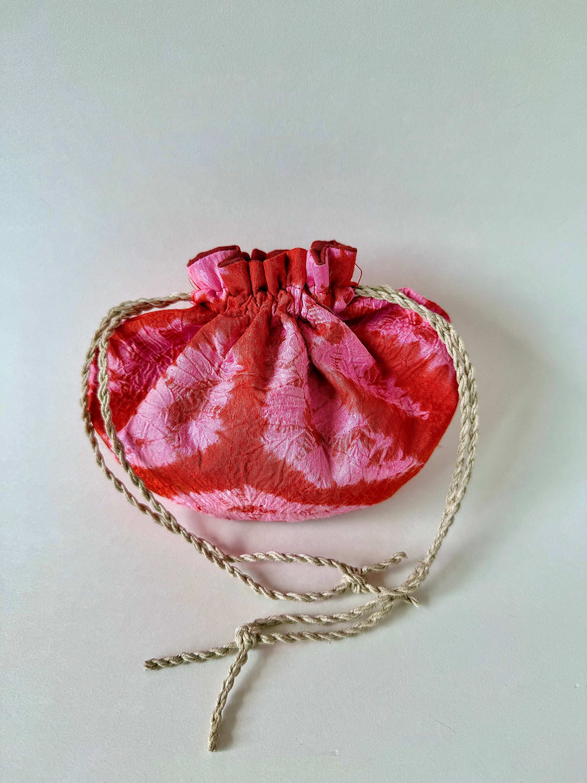 Backside of cinched hemp drawstrings on pink and red kimono silk pouch
