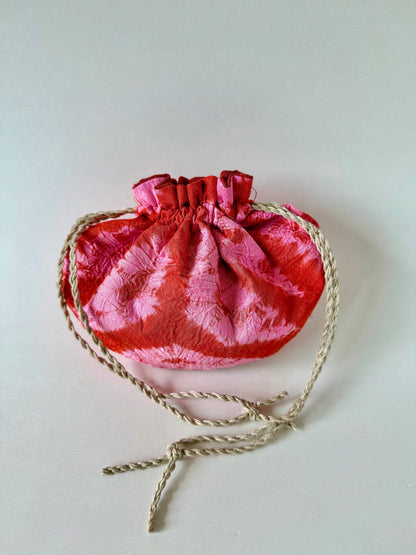 Backside of cinched hemp drawstrings on pink and red kimono silk pouch