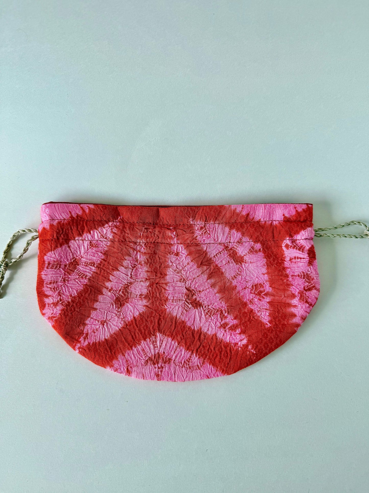 Backside of flat laying red and pink kimono silk drawstring pouch with 100% hemp drawstrings