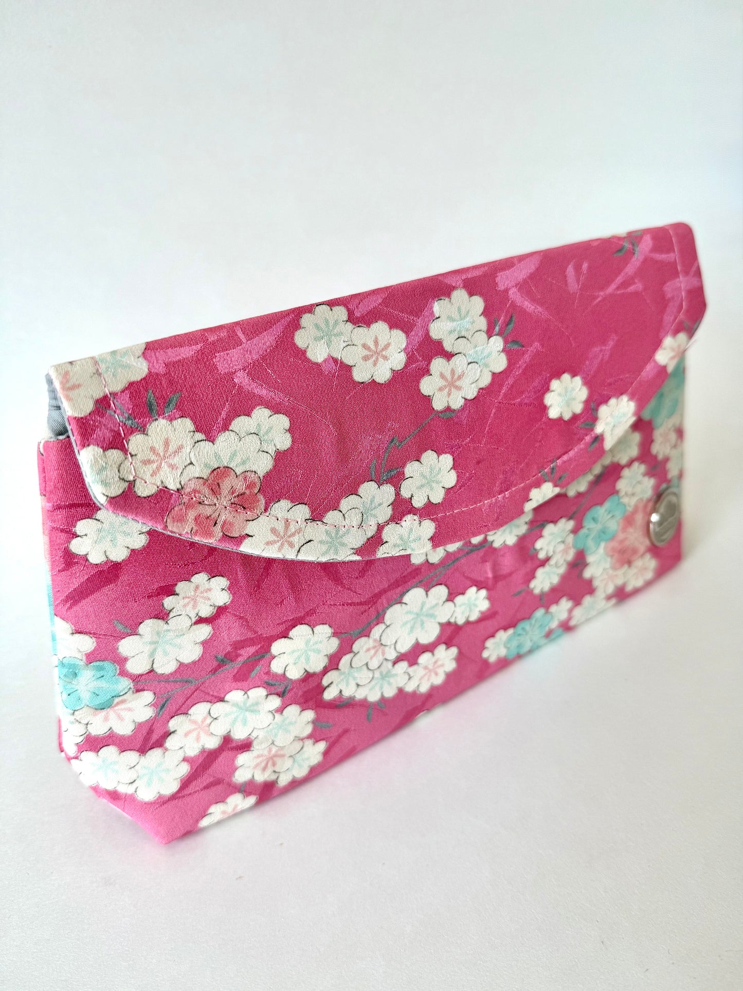 Front left angle view of cherry blossom kimono silk showing blue, pink and white sakura and top stitching 