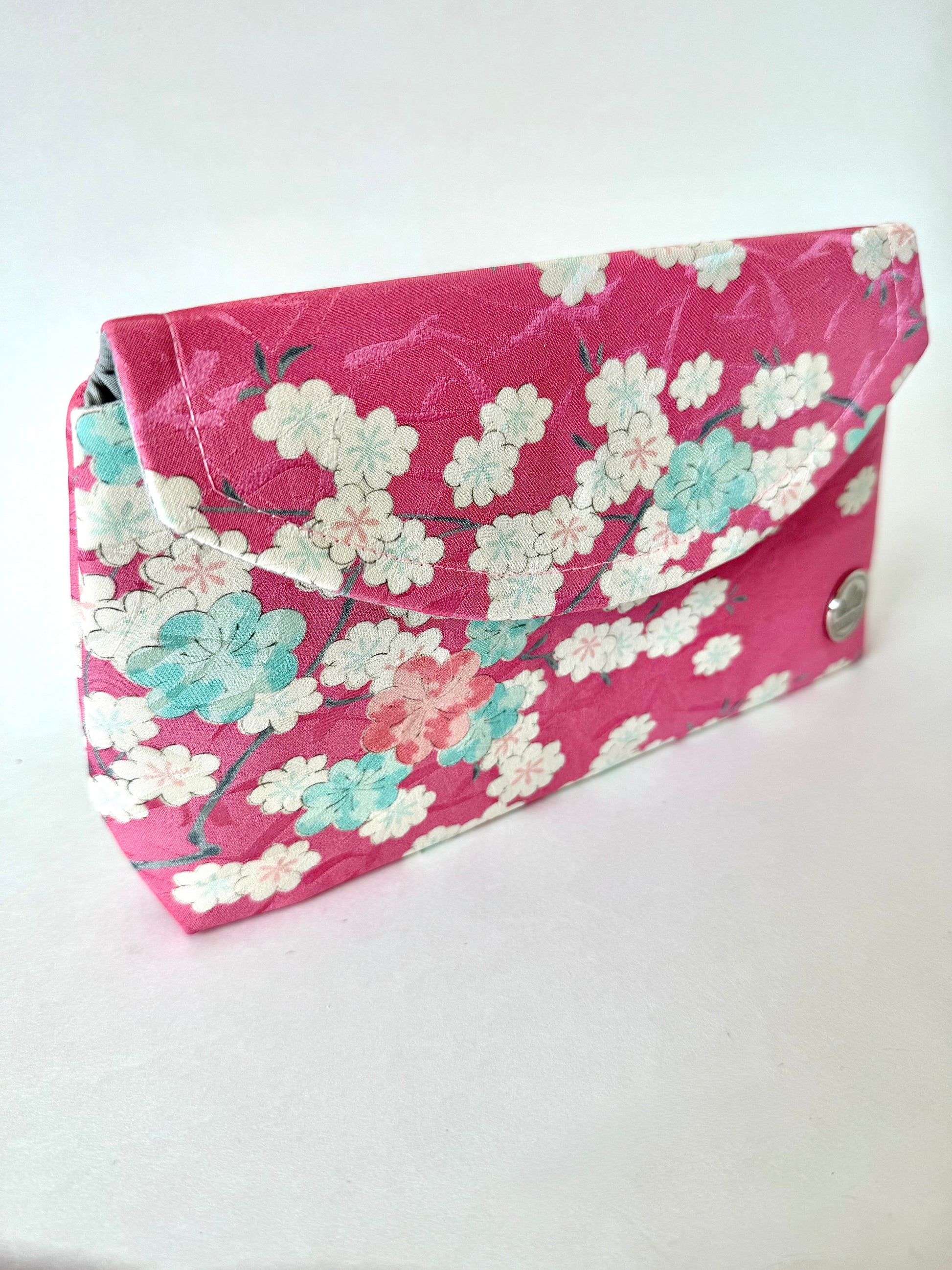 Angled view of fold over clutch bag with pink kimono silk exterior