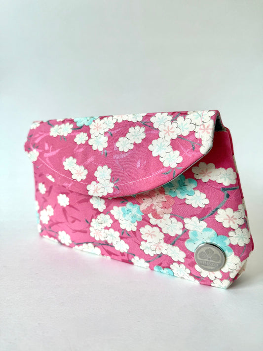 Angled view of pink kimono clutch with cherry blossom motifs in white, pink, and blue