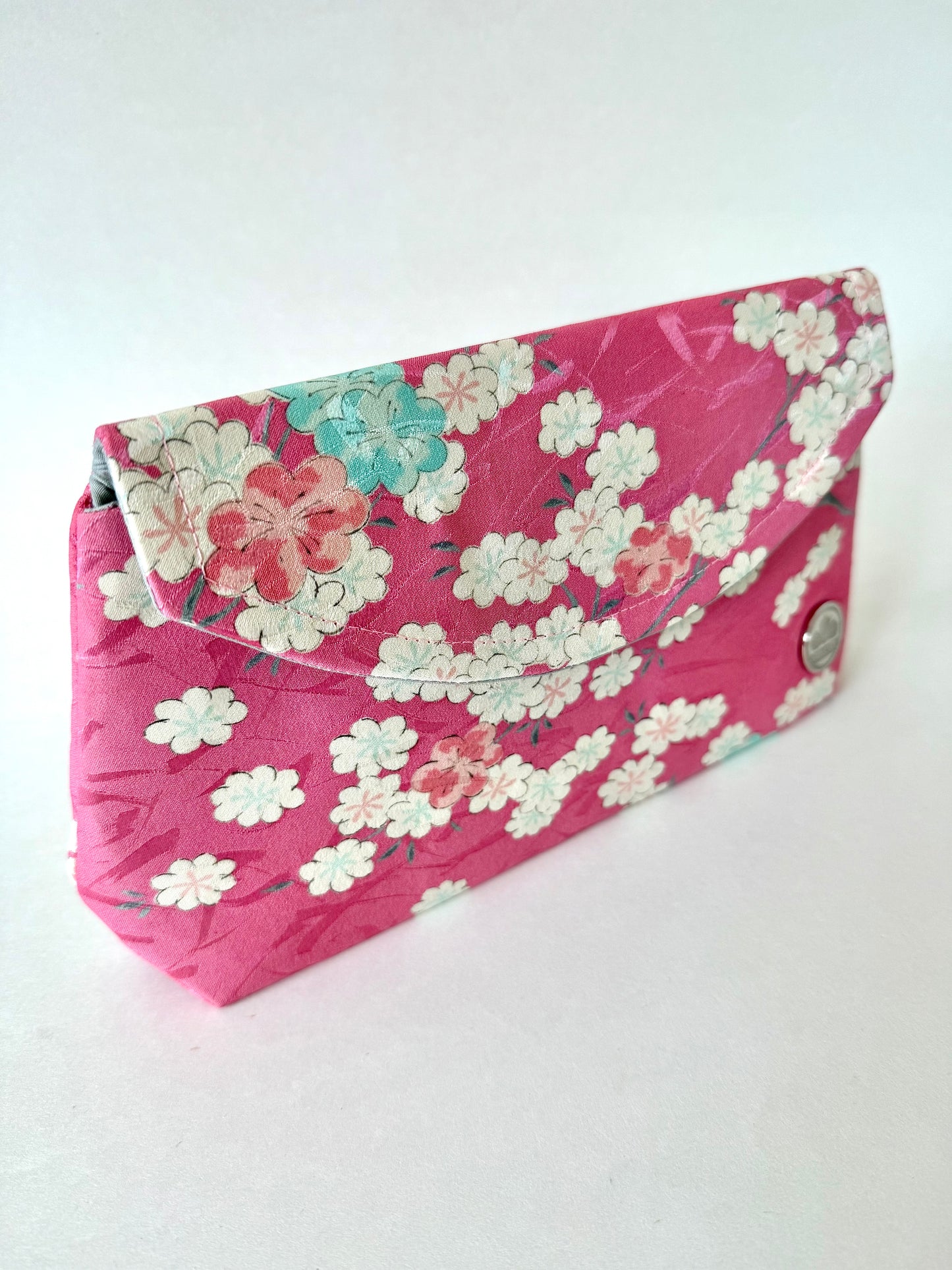 Front left angle of pink kimono silk clutch showing pink, blue, and white sakura flowers