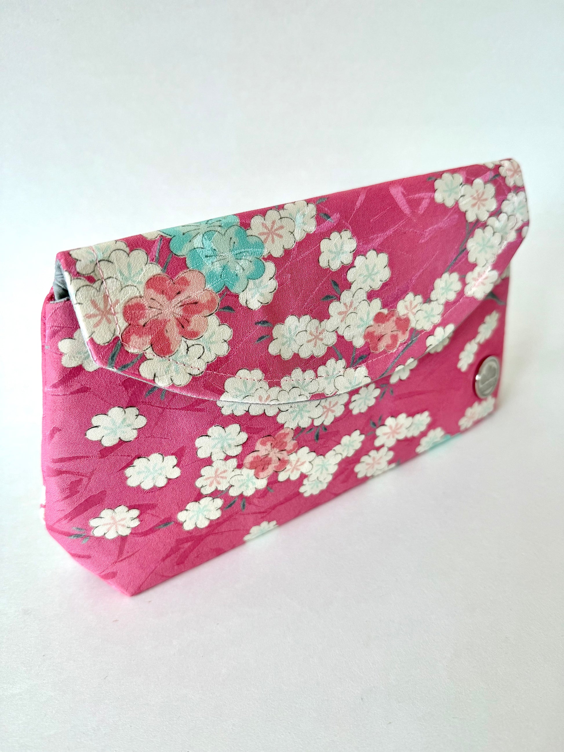 Front left angle of pink kimono silk clutch showing pink, blue, and white sakura flowers