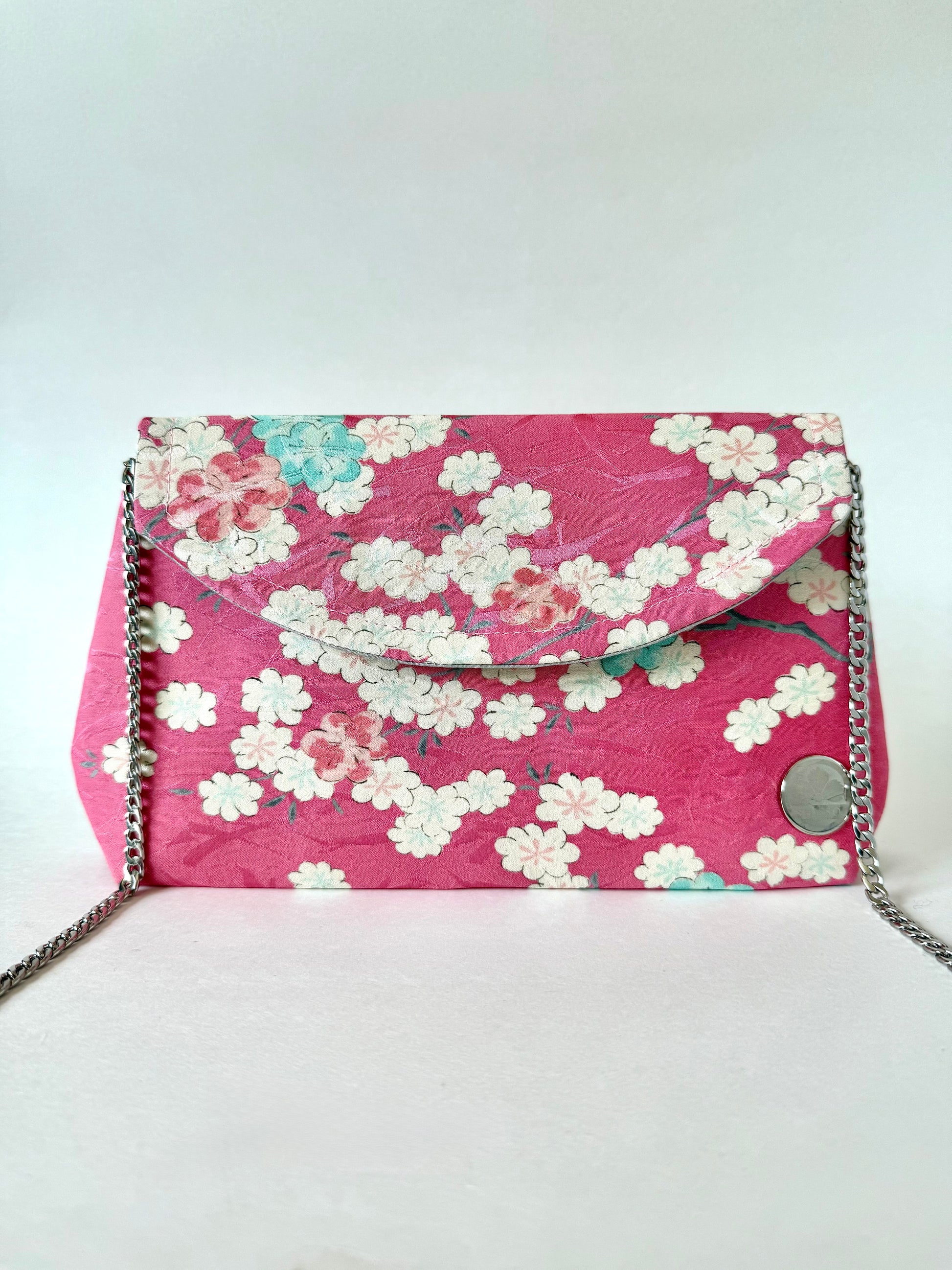 Front of pink silk kimono clutch with sakura pattern and detachable chain strap