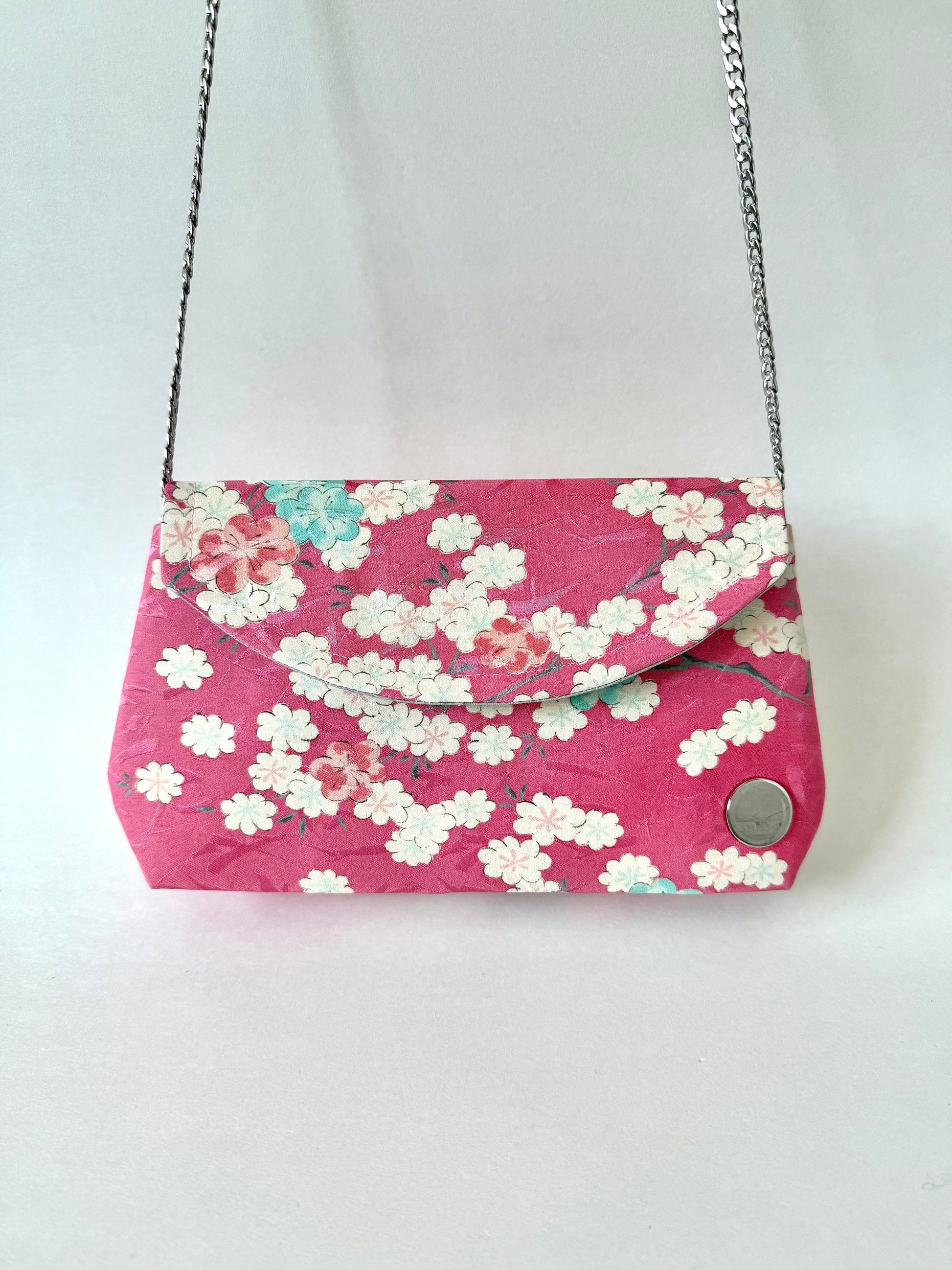 Kimono clutch bag with cherry blossom motif hanging from metal chain strap