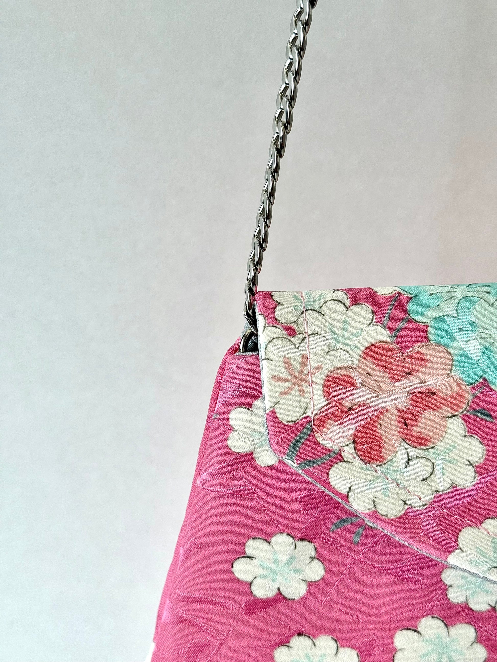 Close up of detachable chain connected to the interior of pink kimono silk clutch bag