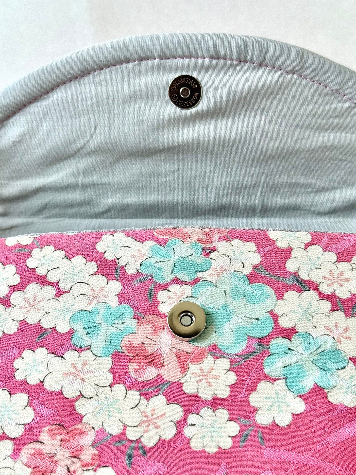 Magnetic closure of pink kimono silk clutch bag with silver cotton broadcloth interior