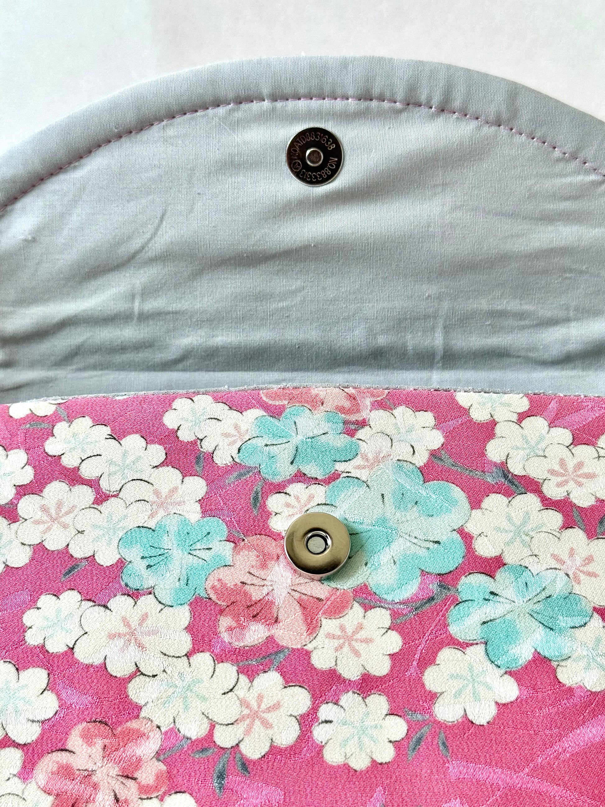 Magnetic closure of pink kimono silk clutch bag with silver cotton broadcloth interior