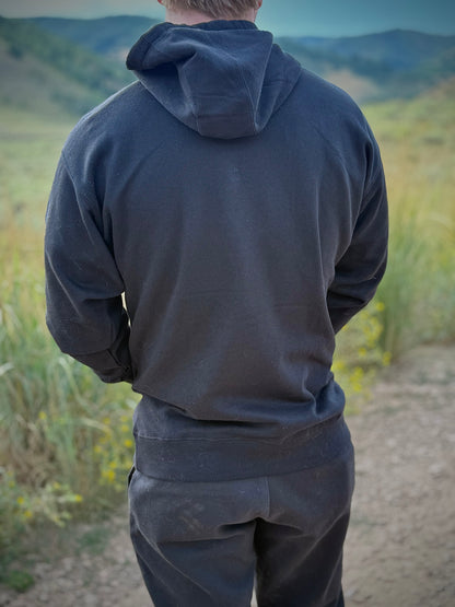 Back view of model wearing black Japanese design yokai hoodie in nature background, showing plain black fabric and clean minimalist design.
