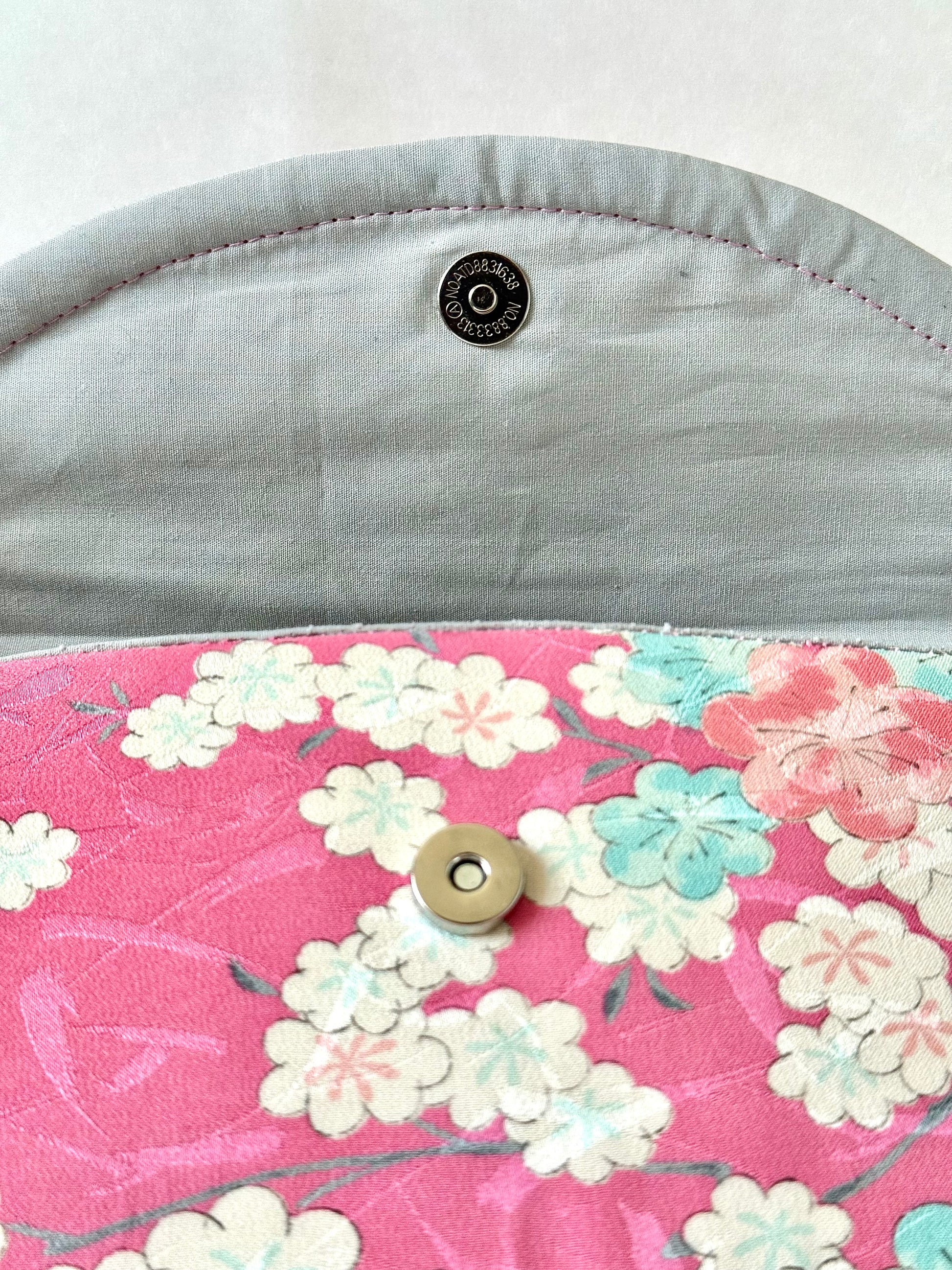Close up of magnet closure on pink kimono clutch with silver cotton lining