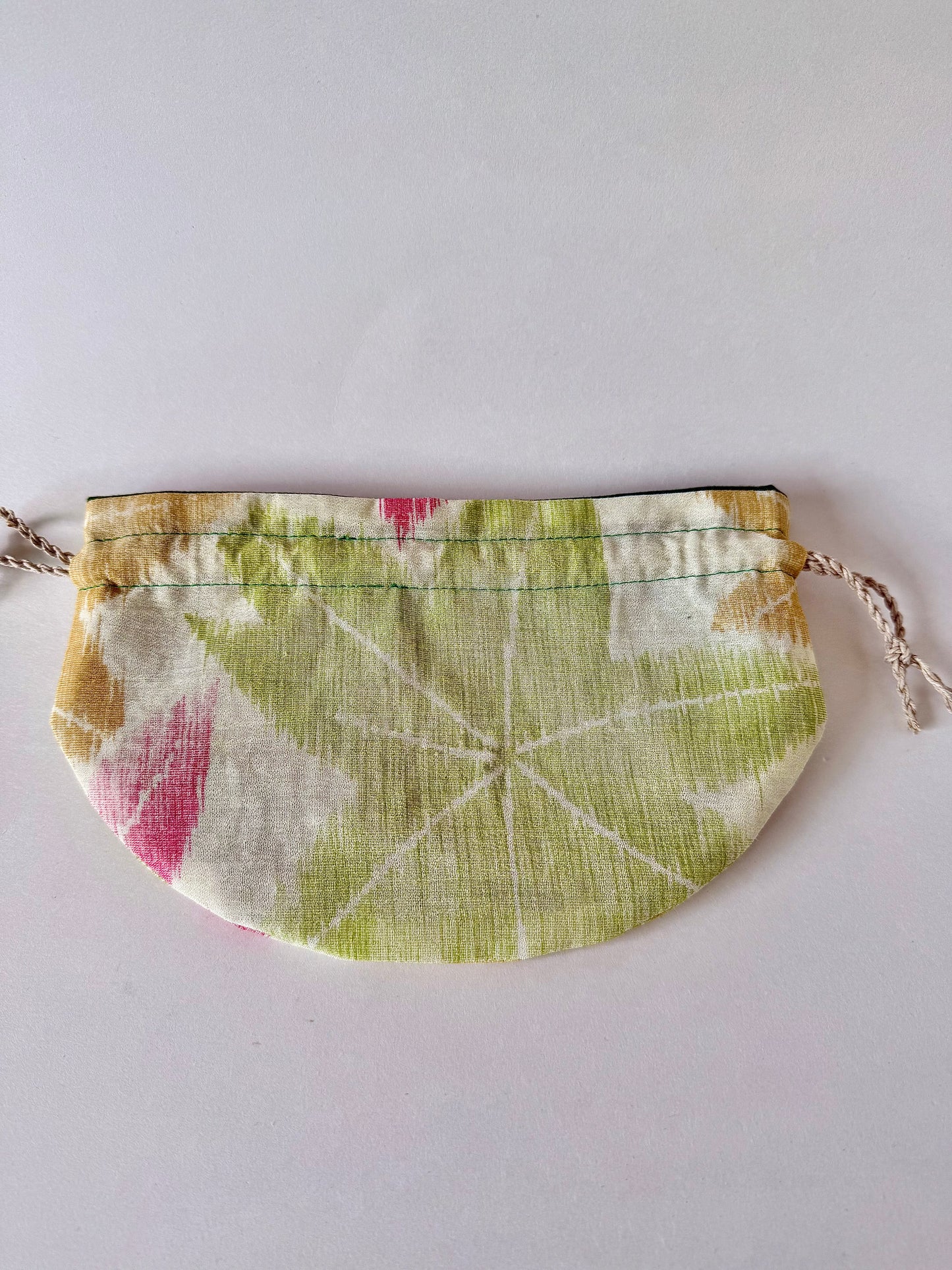 Backside view of flat laying woven kimono silk drawstring bag with large green momiji motif in the center