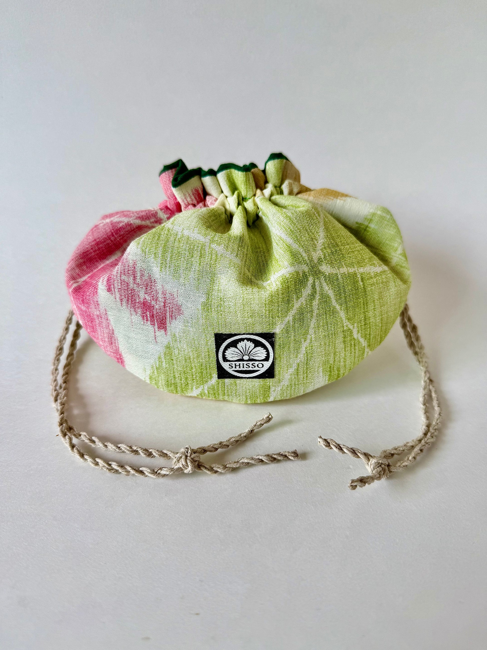 Front view of kimono silk pouch with green and red maple leaves pattern, cinched closed with natural hemp drawstrings