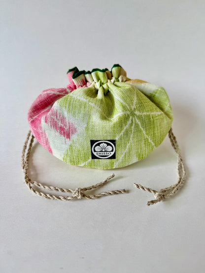 Front view of kimono silk pouch with green and red maple leaves pattern, cinched closed with natural hemp drawstrings