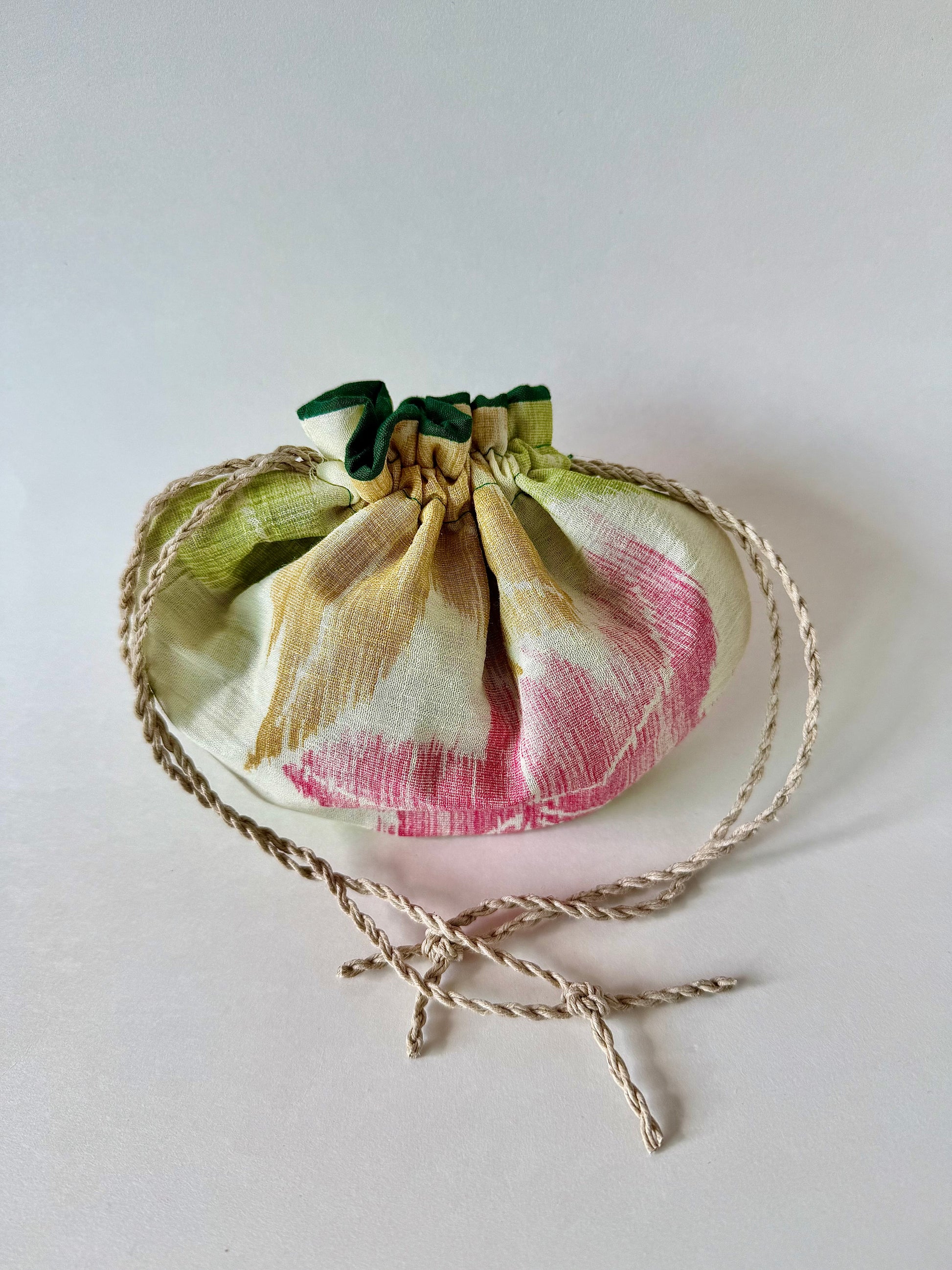 Cinched closed beige kimono silk drawstring pouch with red, yellow, and green Japanese maple leaf designs and hemp cords
