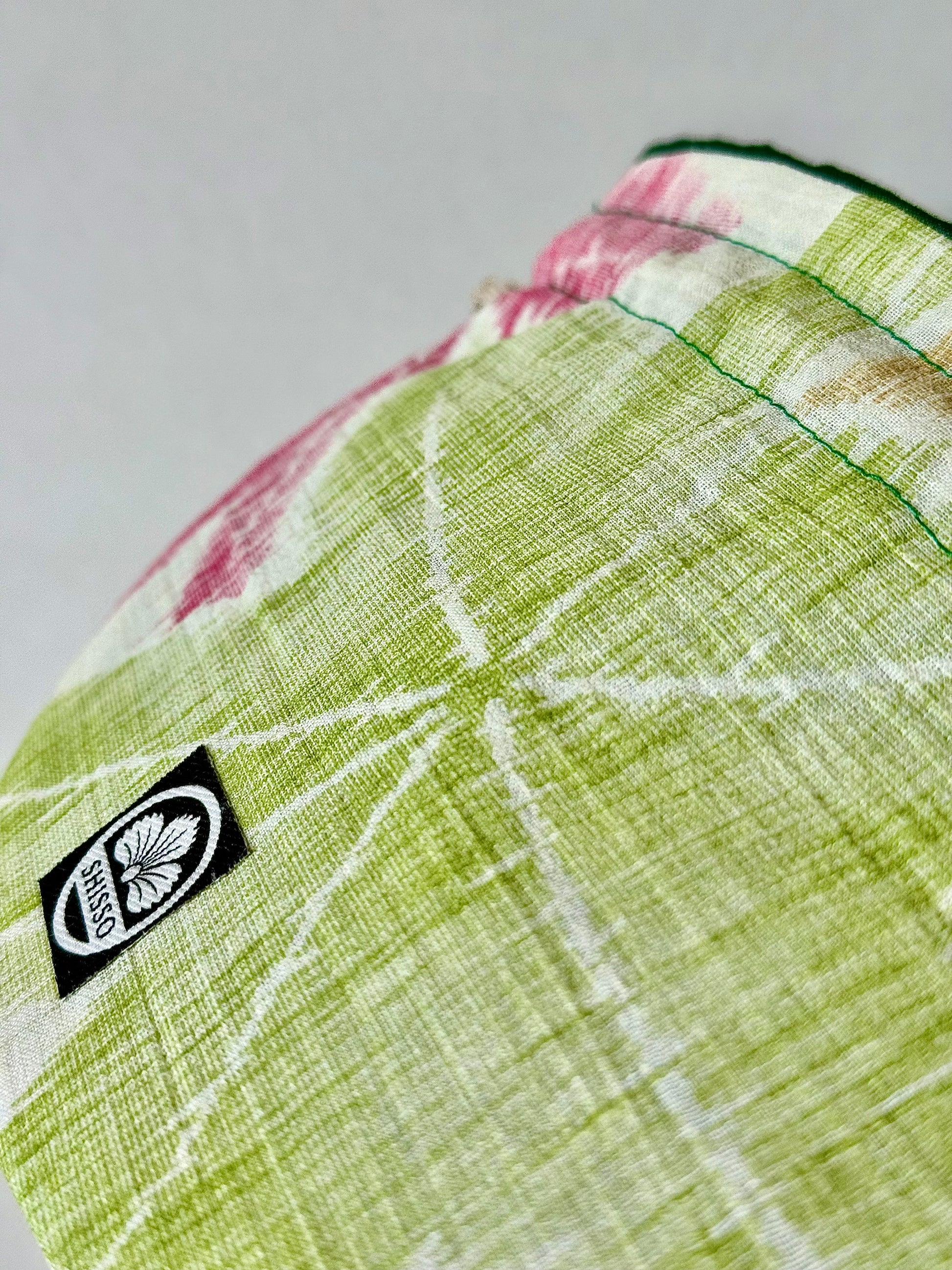 close up view of woven textured kimono silk with green and red Japanese maple leaf designs