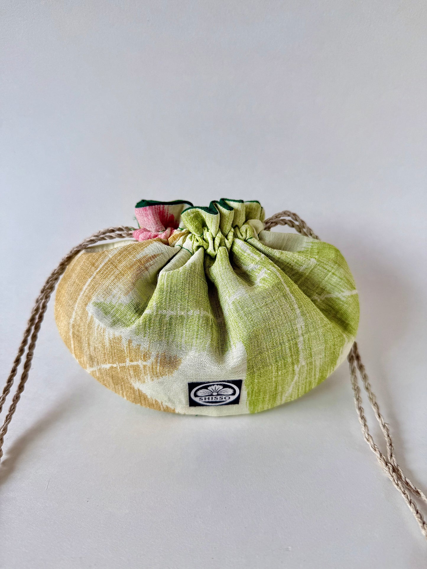 small off white kimono silk pouch with green, yellow, and red maple leaf designs, cinched closed with natural hemp drawstrings