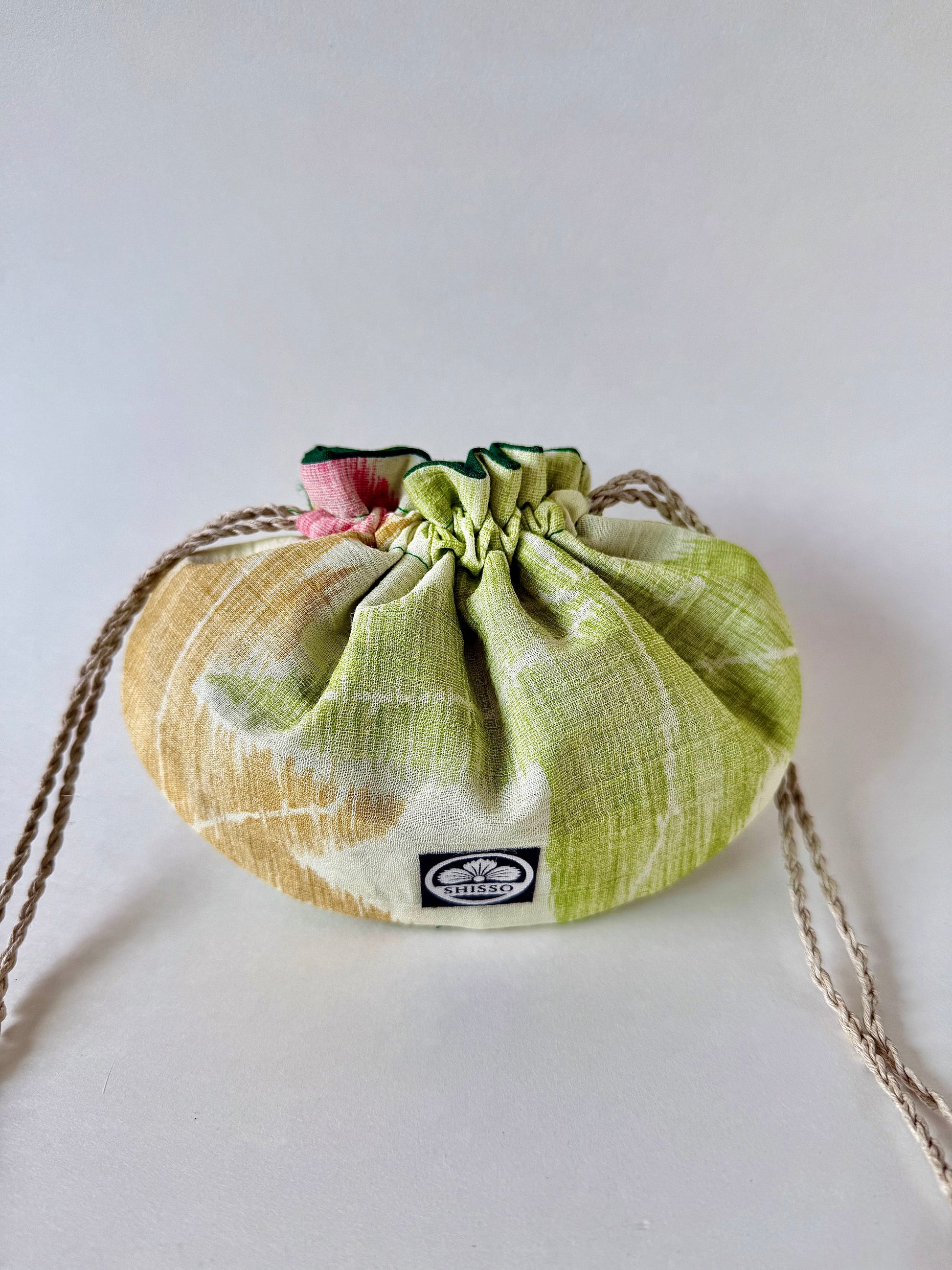 small off white kimono silk pouch with green, yellow, and red maple leaf designs, cinched closed with natural hemp drawstrings