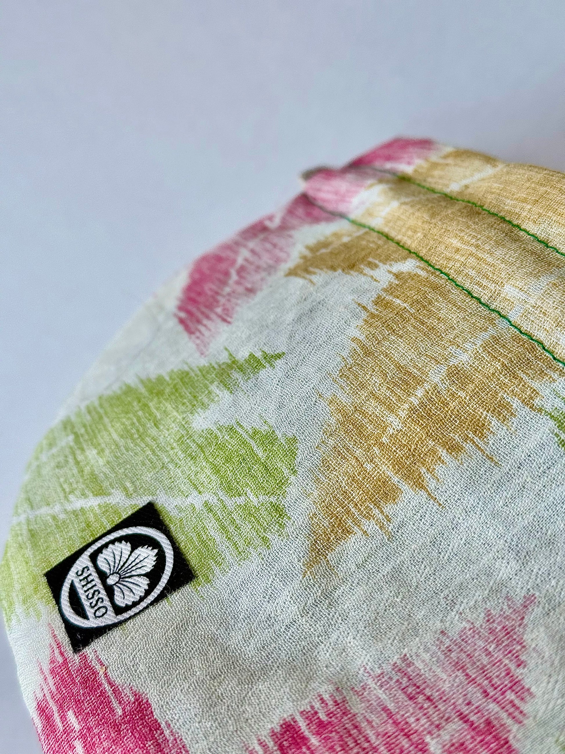 Close up showing texture of beige sha silk with green, yellow, and red Japanese maple leaf pattern