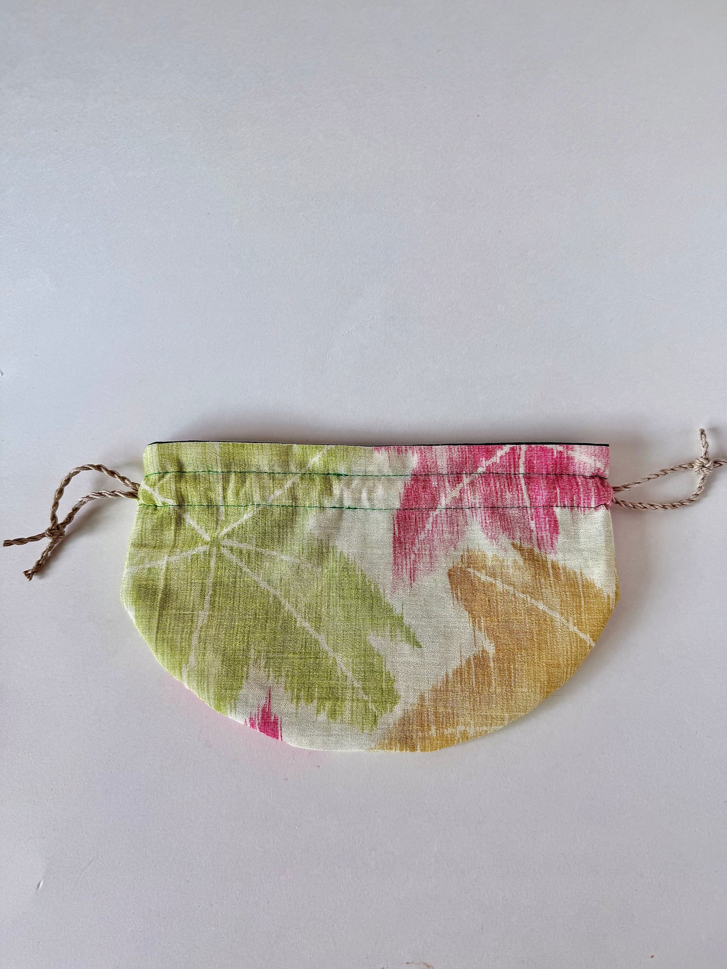 backside view of flat laying beige sha silk drawstring pouch with green, red, and yellow Japanese maple leaf design