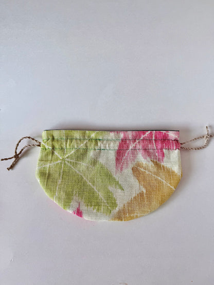 backside view of flat laying beige sha silk drawstring pouch with green, red, and yellow Japanese maple leaf design