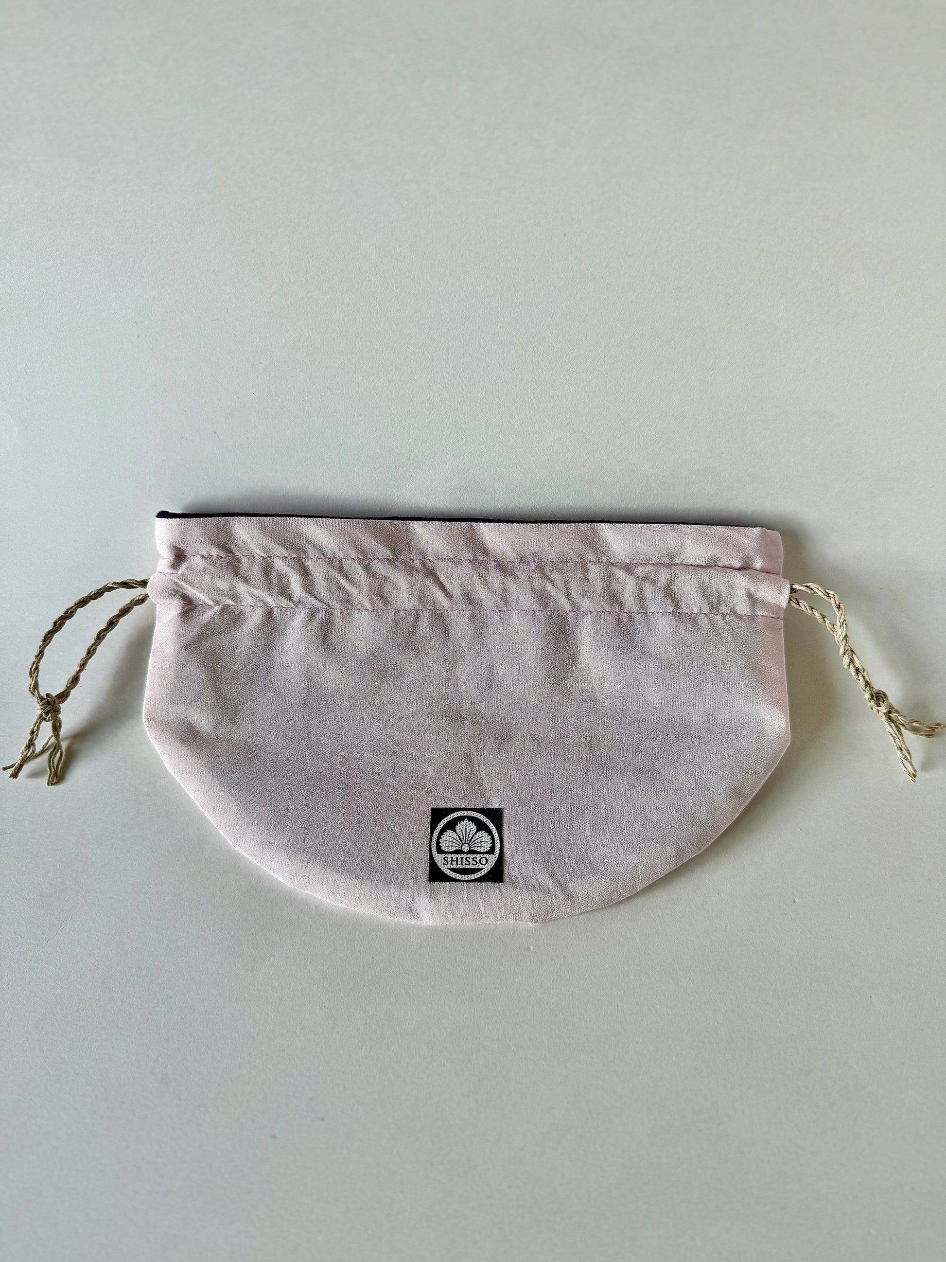 Solid light pink kimono silk drawstring pouch laying flat with tied hemp cord drawstrings