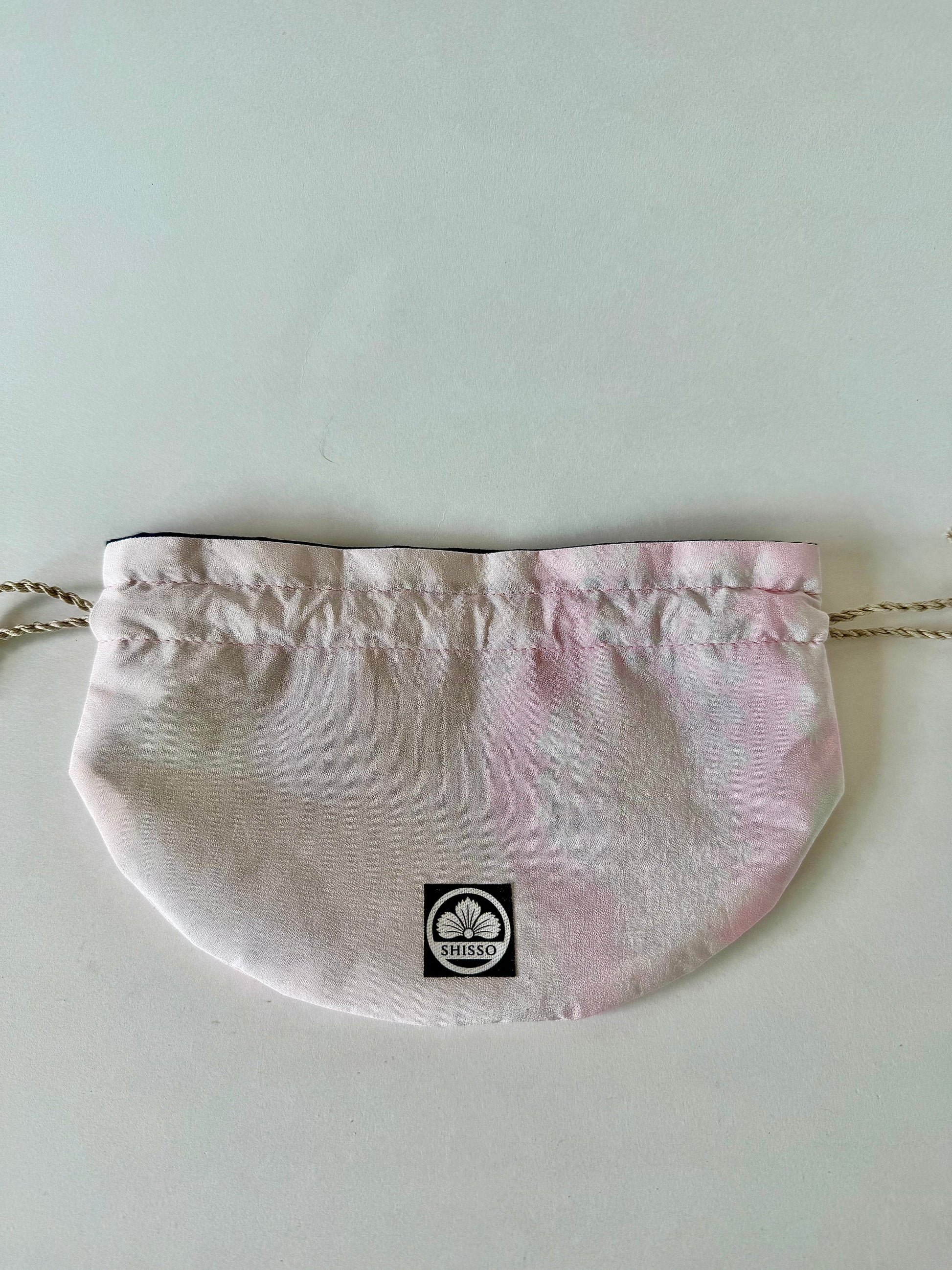 Front view of flat laying pink kimono silk drawstring bag with darker pink accents