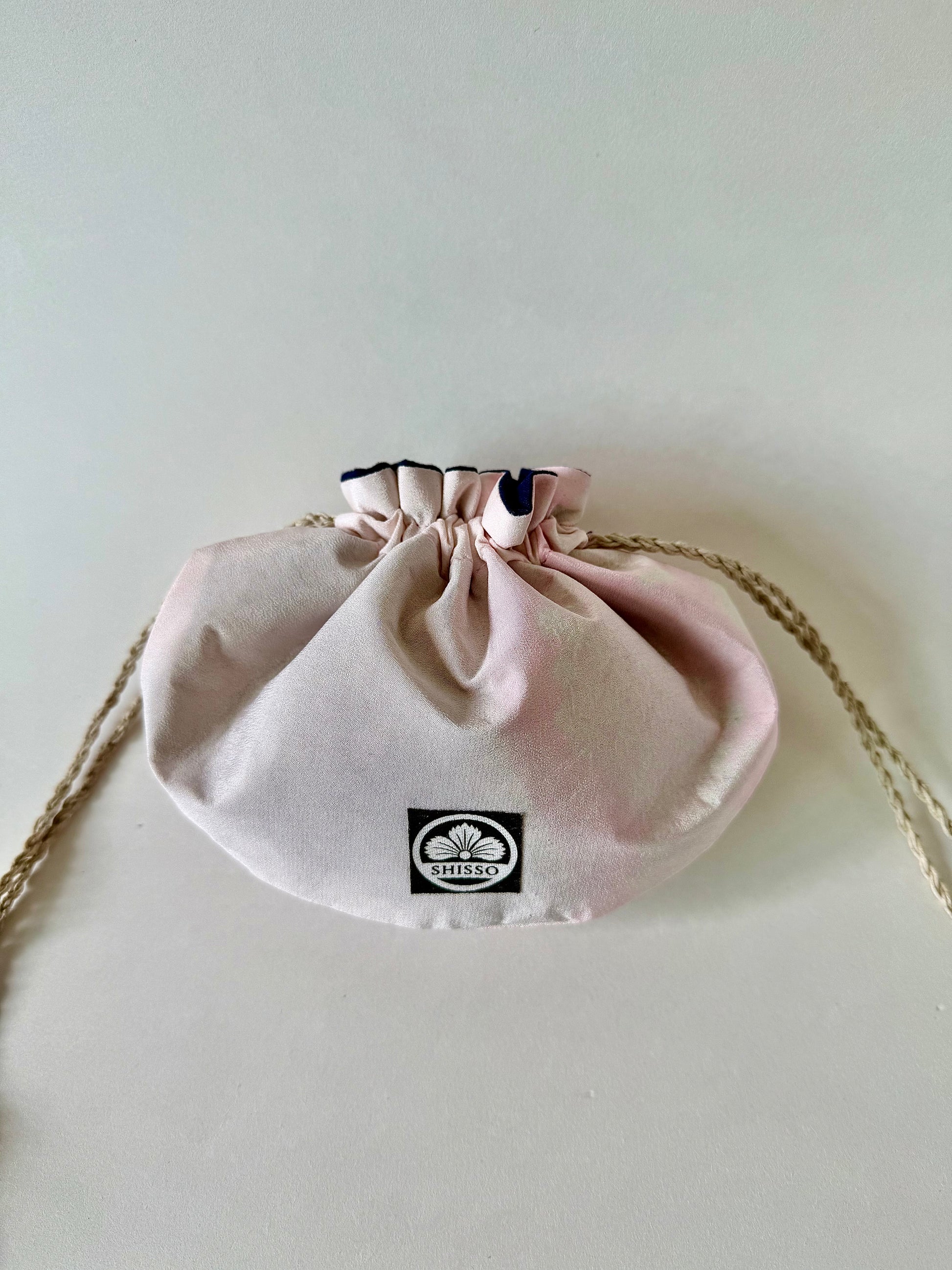 Light pink kimono silk drawstring bag with darker pink accents and natural colored hemp drawstrings cinched