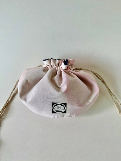 Light pink kimono silk drawstring bag with darker pink accents and natural colored hemp drawstrings cinched