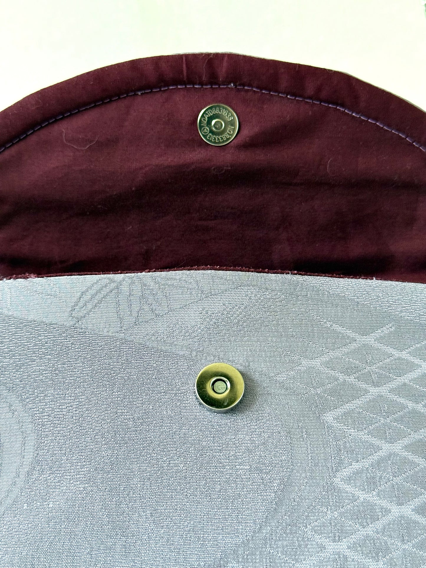 Silver colored magnetic closure on purple chirimen silk clutch with wine colored cotton broadcloth interior