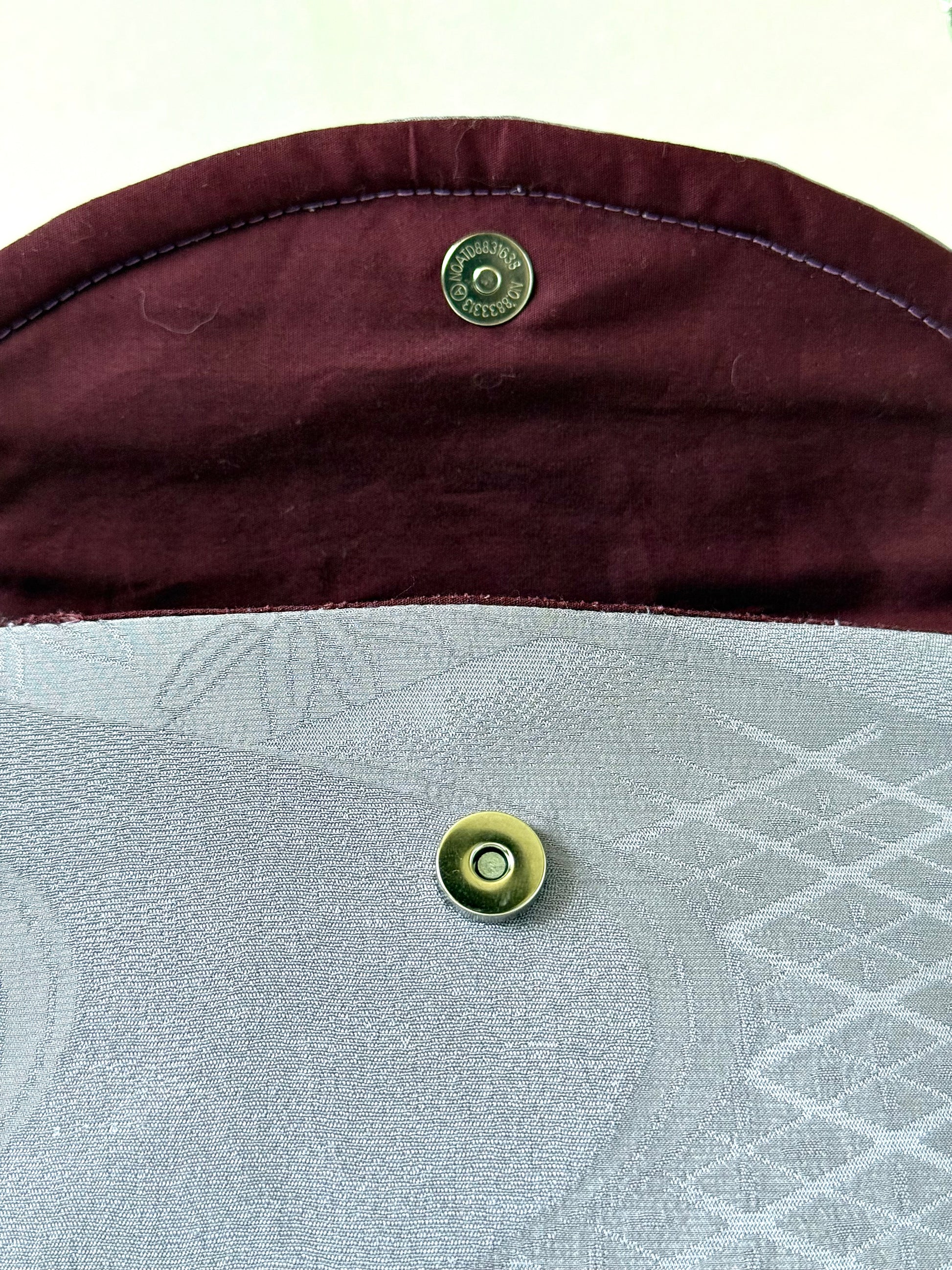 Silver colored magnetic closure on purple chirimen silk clutch with wine colored cotton broadcloth interior
