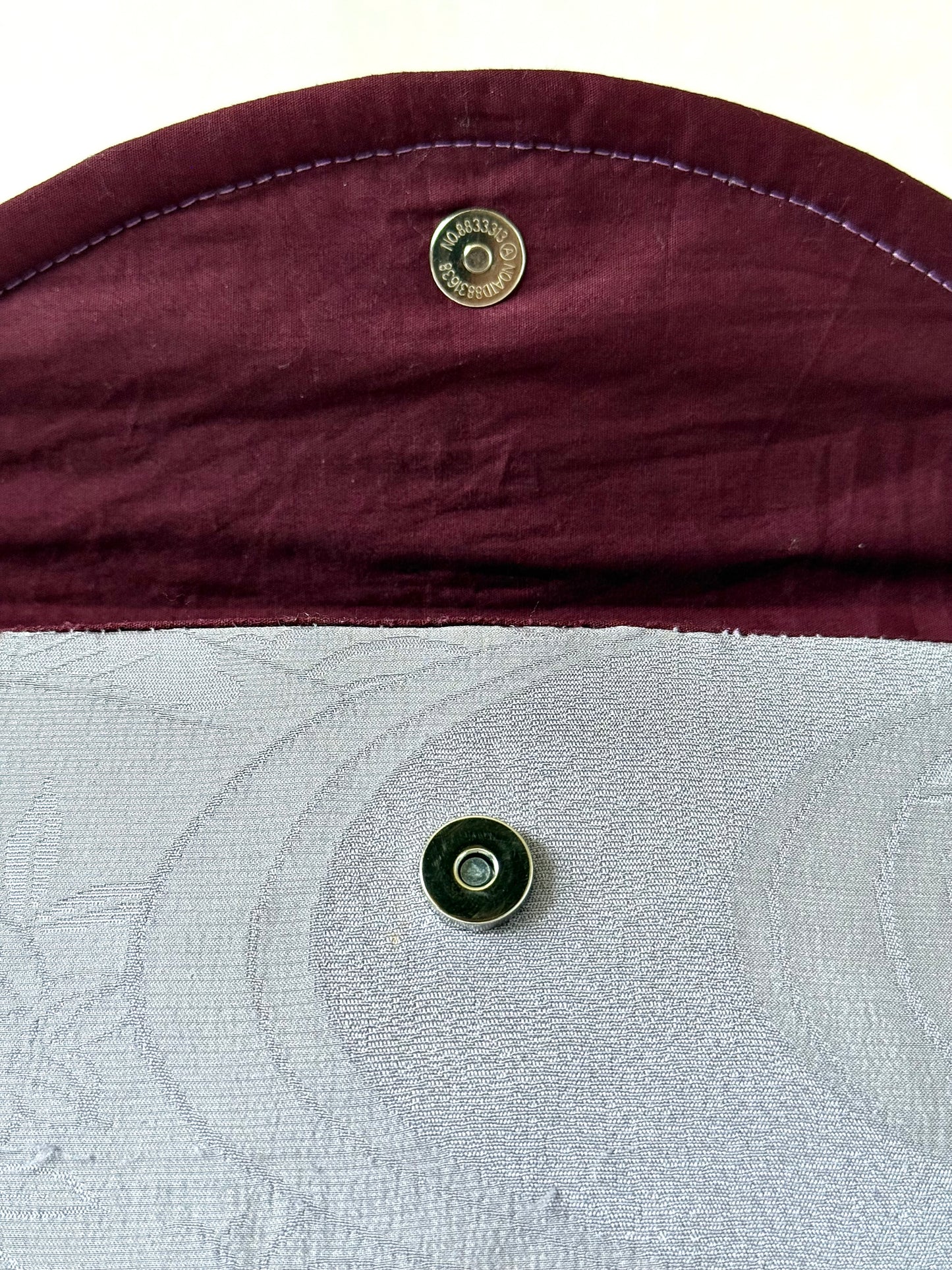 Close up of magnetic closure on the flap of handmade fold over clutch bag